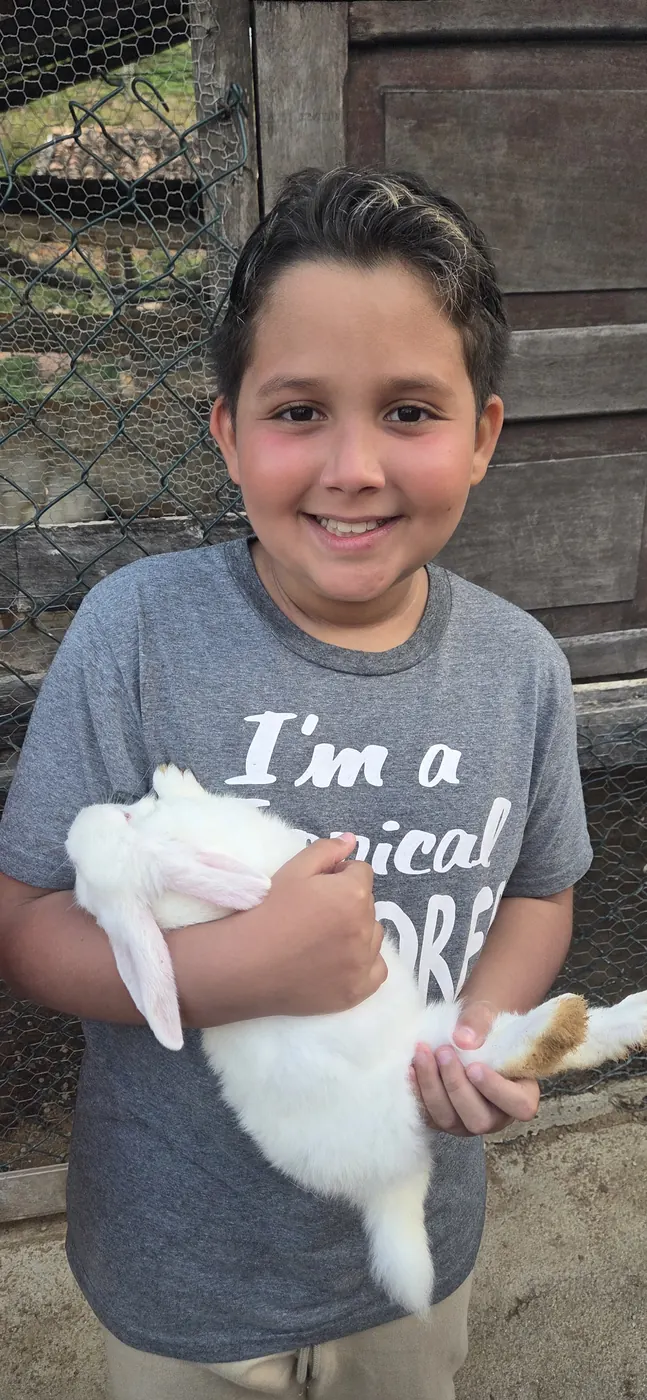 Menino sorrindo com um coelho branco nos braços