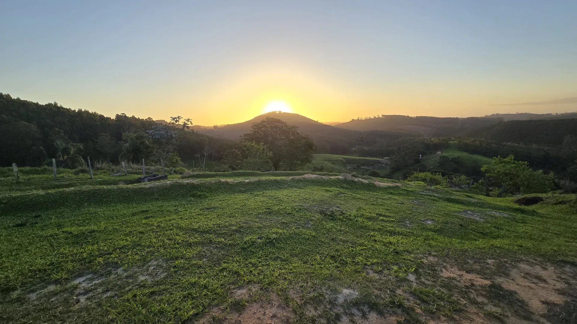 Pôr do sol atrás do morro, visto do pasto da fazenda