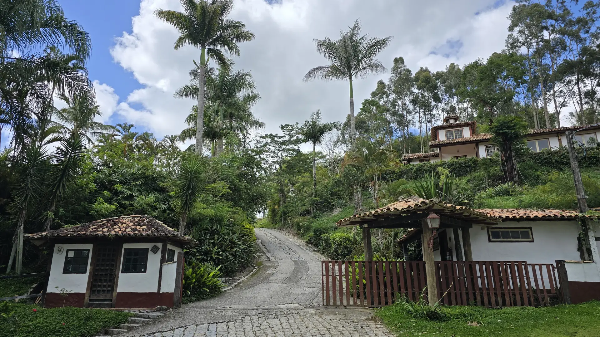 Chegada ao Hotel Fazendão: estrada entre palmeiras, casas brancas de telhado colonial e a mata ao fundo